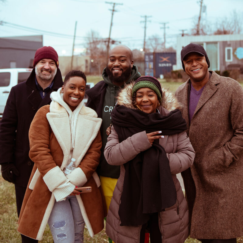 Photo by Lunar Haus. Five people outside on cold day, smiling